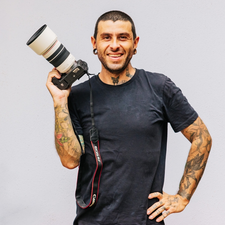 Andy Marin, surf photographer, smiling with a camera and telephoto lens