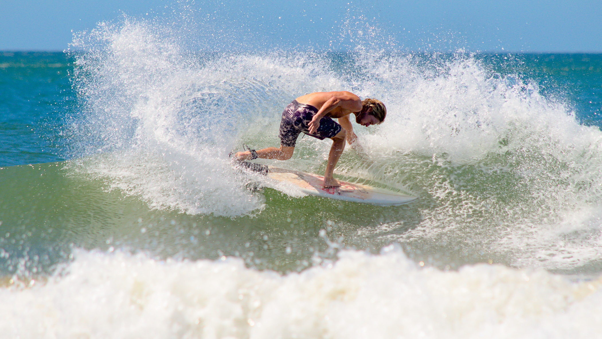 Surfer bei einer harten Kurve durch die Gischt an der Playa Guiones