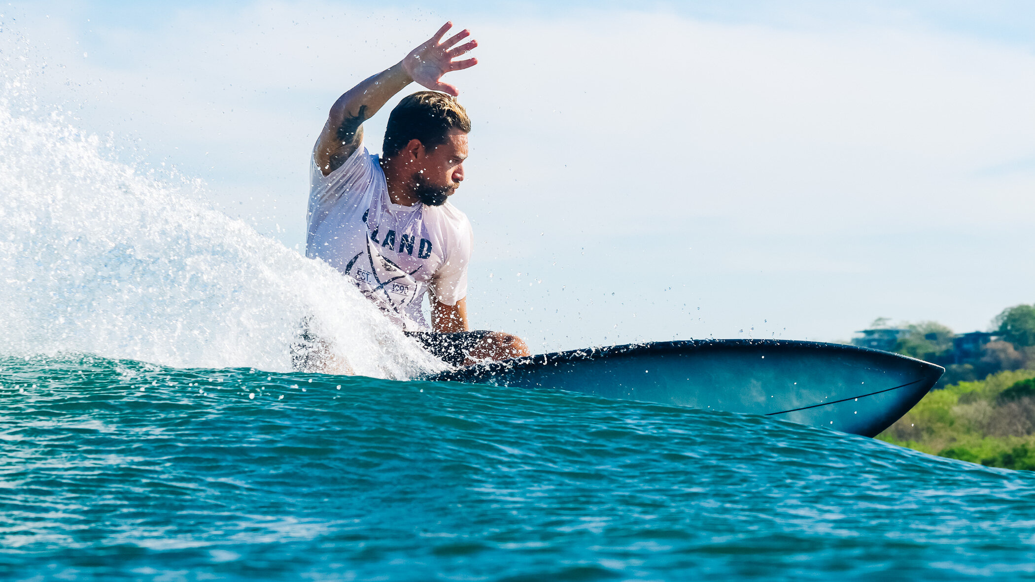 Surfer in a white T-shirt carving a wave at Playa Guiones