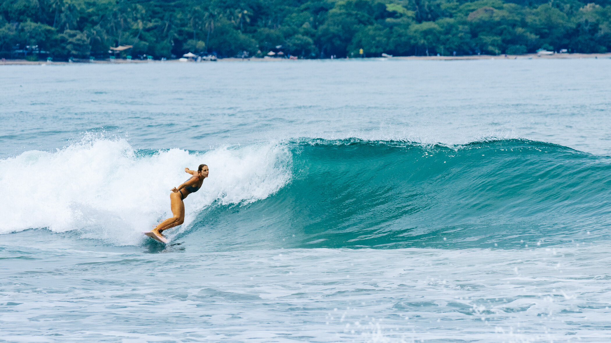 Chica haciendo un bottom turn en una ola limpia en Playa Grande